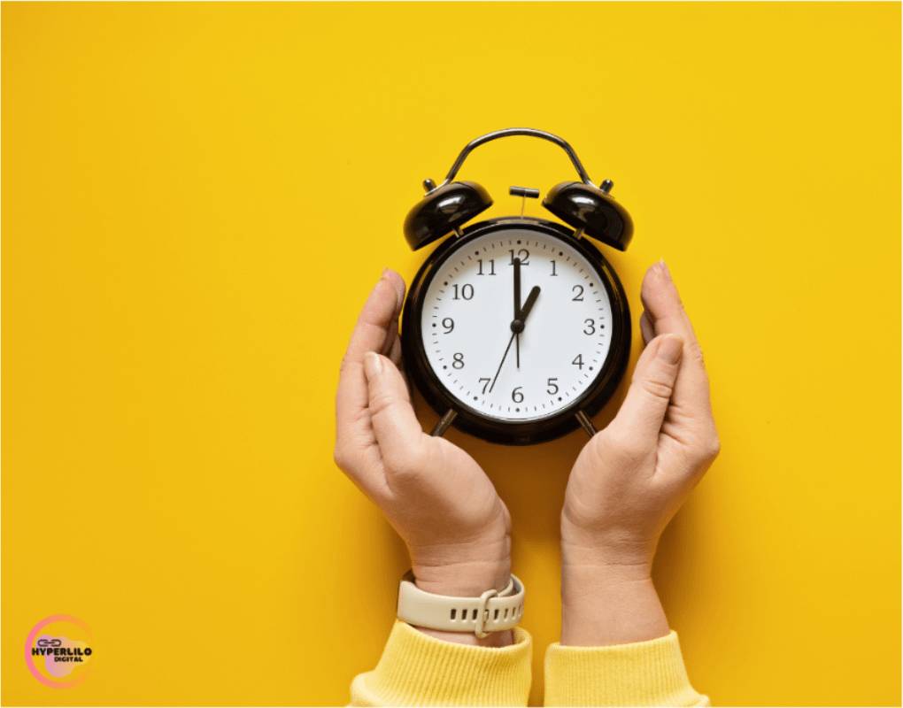 Image Alt text: Hands hold a black alarm clock on a yellow background.