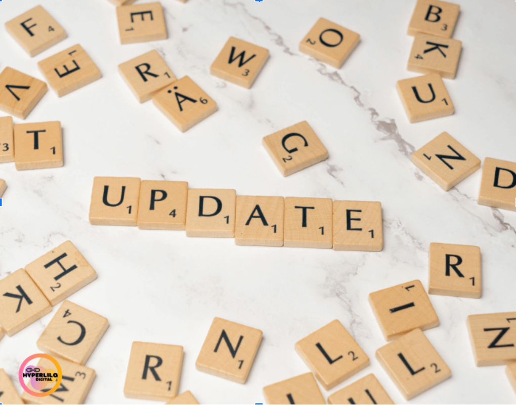 A top-down view of Scrabble tiles on a white marble surface, spelling "UPDATE" in the center, surrounded by scattered letter tiles.